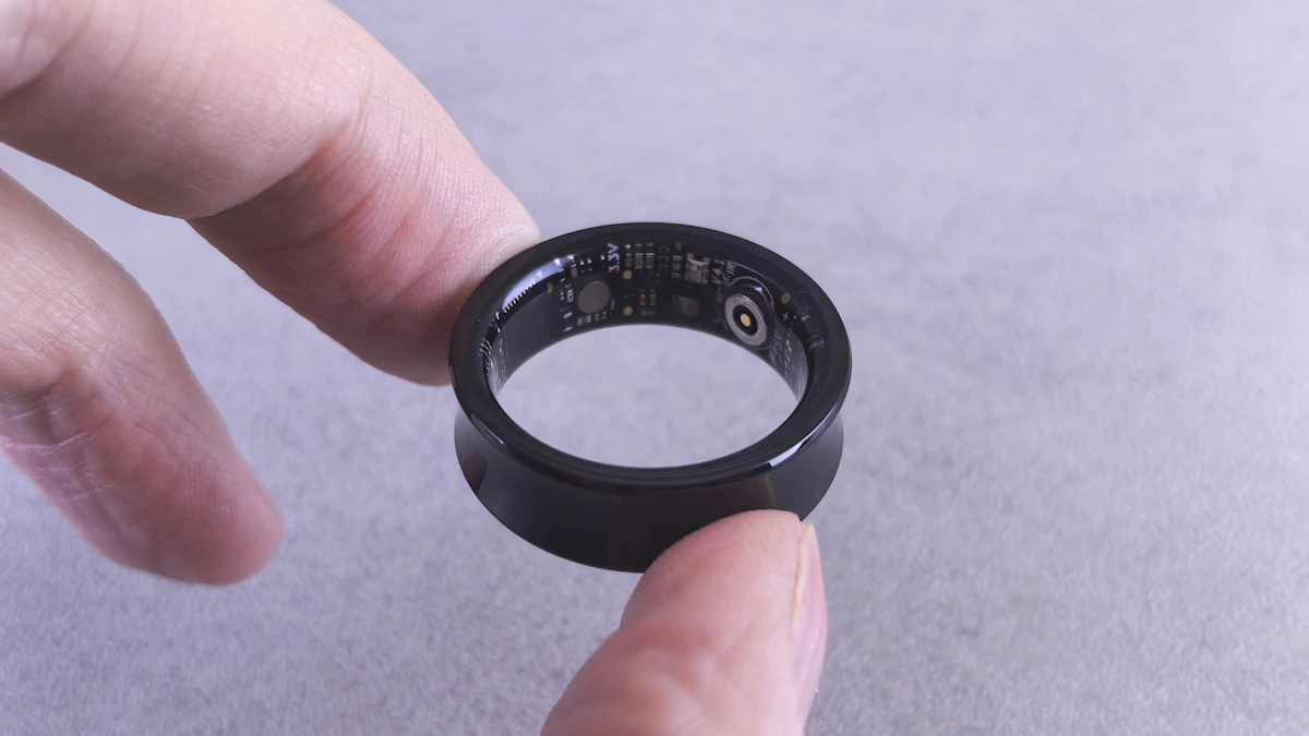 Fingers holding a black smart ring with visible circuits, similar to the Ultrahuman Ring Pro now in US stores