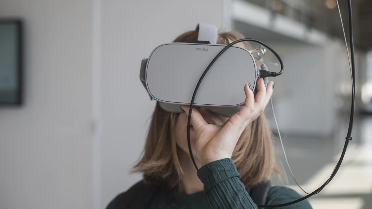 Woman holding a pair of white and black XR goggles, the kind of wearable display the Xreal Aura glasses compete with